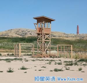 A replica of one of the camp��s watch towers in the exact place where it once stood. The smoke stack of the hospital is in the background.  