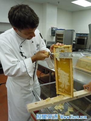 Executive sous chef Ian Bens scrapes a thin layer of wax off the bee frame before the honey is extracted.