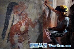 Conservator Angelyn Bass cleans and stabilizes the surface of a wall of a Maya house that dates to the 9th century A.D. The figure of a man who may have been the town scribe appears on the wall to her left. 